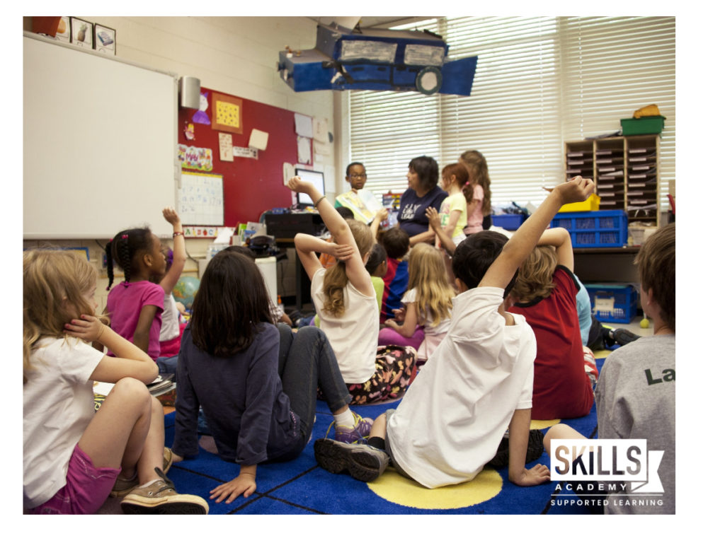 一群孩子坐在教室的地板上，听老师讲课:今天学习我们的教育课程