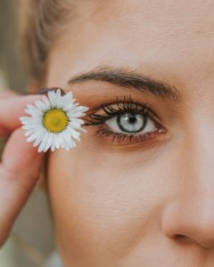 用美容产品装饰的女人的侧脸她有一双灰蓝色的眼睛，眼睛旁边放着一朵花