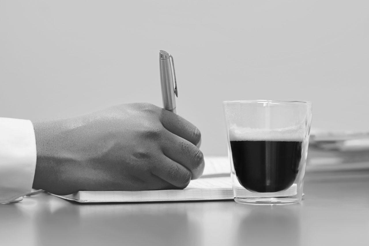 一张纸上写着一只手，旁边就有一杯咖啡