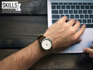 一只男人的手，一只棕色的手表放在电脑键盘上