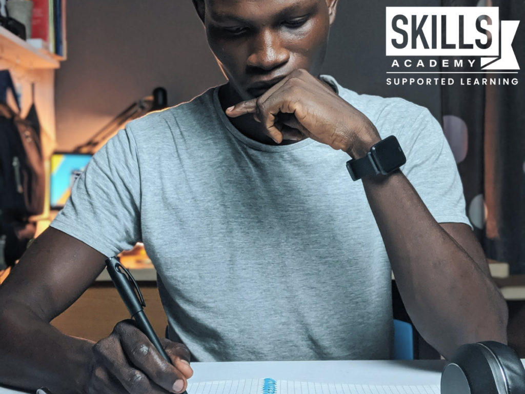 一个年轻人坐在桌子前做作业。申请大学时，你的入学成绩很重要，所以要努力学习。