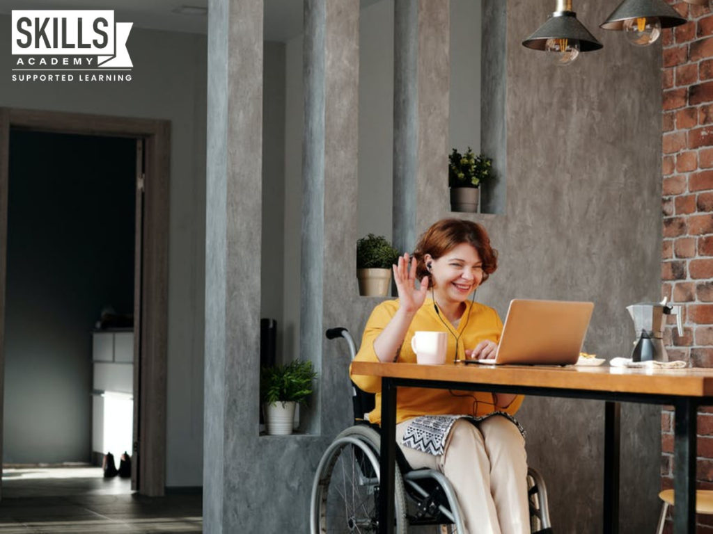 一个学生坐在轮椅上,坐在她办公桌学习课程。让您选择远程学习的学习期间锁定。