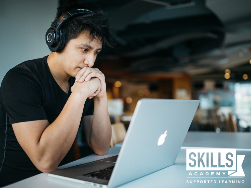 一个年轻人戴着耳机，坐在电脑前阅读泄露的大学入学考试试卷。