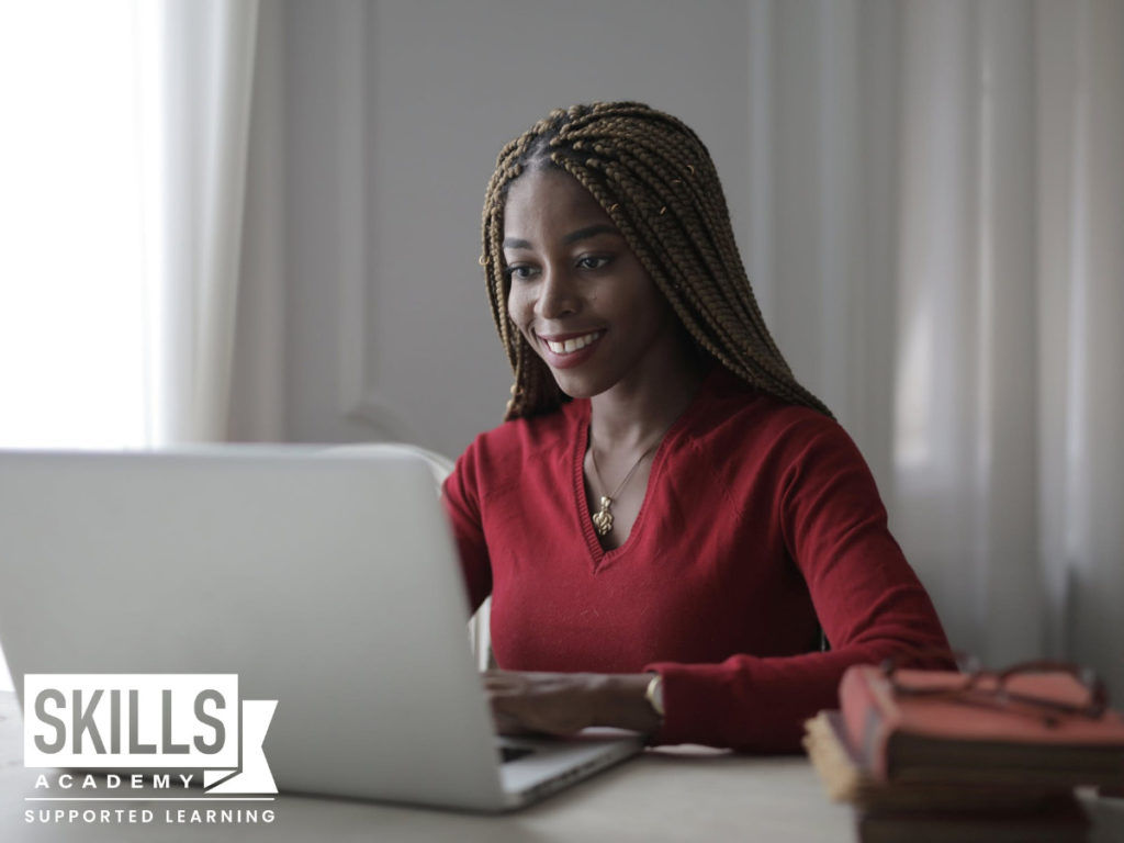 一个穿着红色上衣的年轻女孩，坐在电脑前做关于南非新学科的研究——这意味着什么?