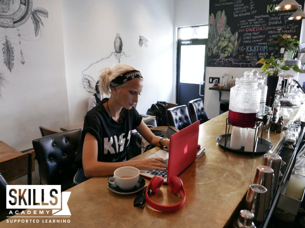 一个年轻的女人坐在咖啡店里,寻找高薪工作没有学历在她的笔记本电脑。