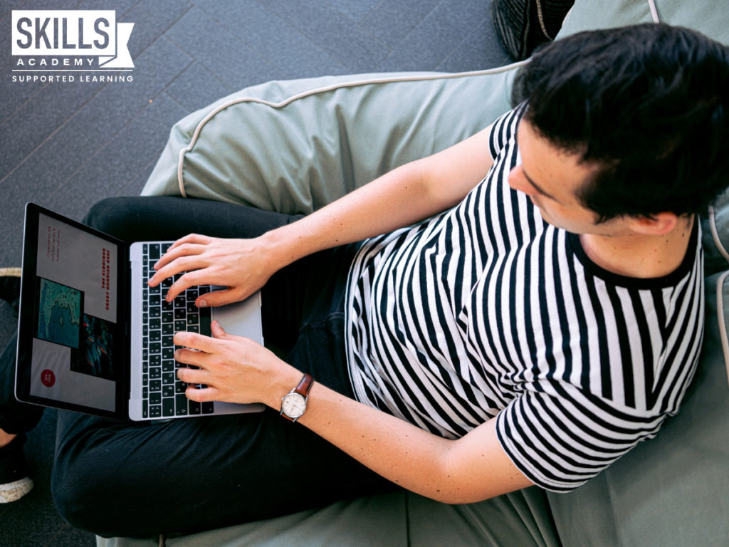 穿着条纹t恤的男子,坐在一台笔记本电脑。从舒适的家中工作时获得的经验作为一个自由职业者。
