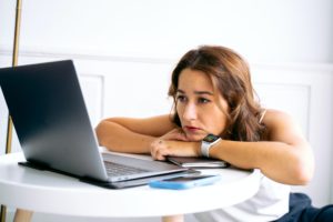 年轻女子看着她的笔记本电脑，同时阅读建议，如果你是裁员