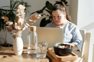 一个女人拿着笔记本电脑围着桌子坐着。以下是如何找到远程工作