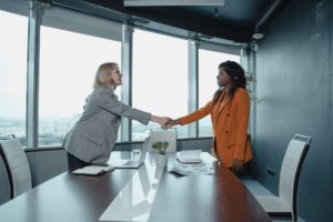两个女人在握手。学习如何以正确的方式协商薪水。