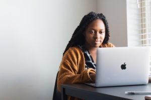 一个小女孩坐在她的笔记本电脑上研究南非最好的管理课程。