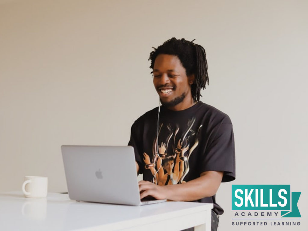 一个年轻人坐在桌子旁，用电脑查找南非最好的管理课程。