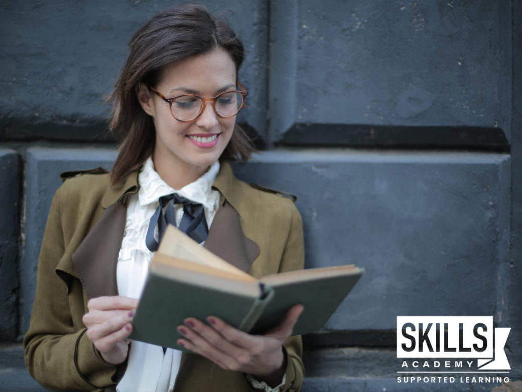 一个年轻的女孩微笑着阅读当你失业时该怎么办。