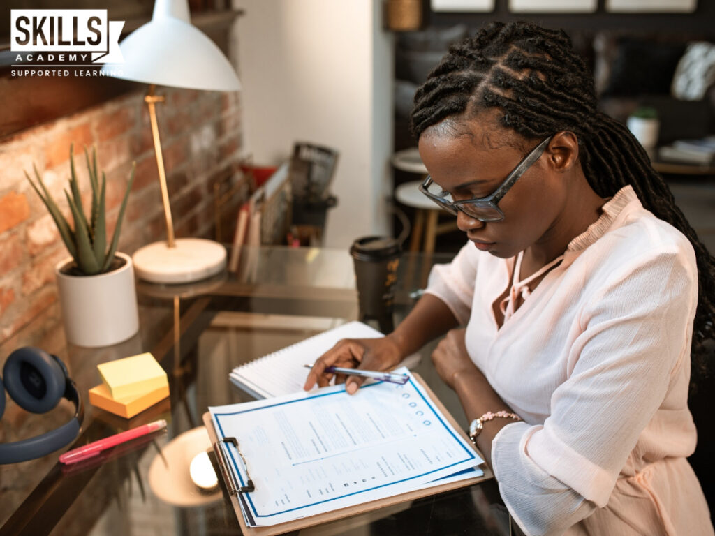 一个女人坐在桌子前，计划她的工作，以坚持她的时间表。时间管理是每个职业需要的11项软技能之一。