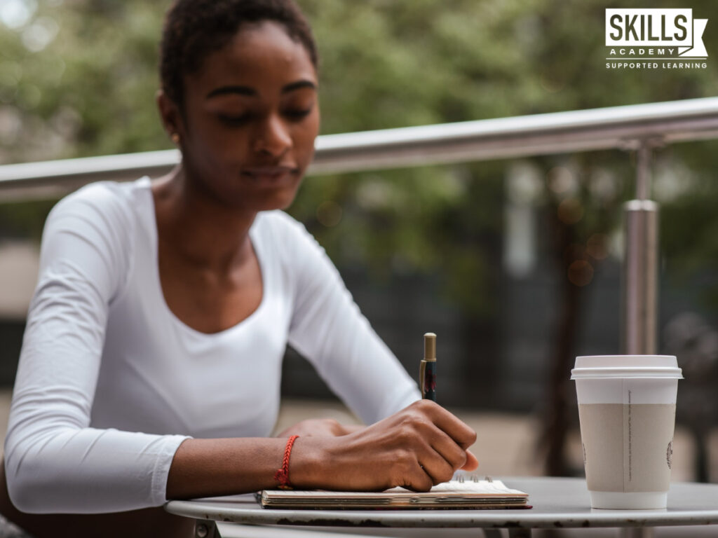 一位女士坐在外面的桌子边，在笔记本上写字。找出我们在这里提供的主要科目。