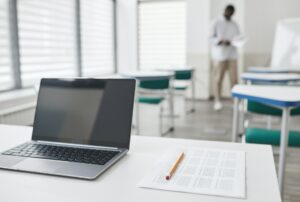 笔记本电脑在桌子上,旁边还有一个纸和笔后有人使用它为国际学院考试登记为2022