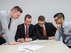 四个人在讨论文件。如何开始企业管理的职业生涯。