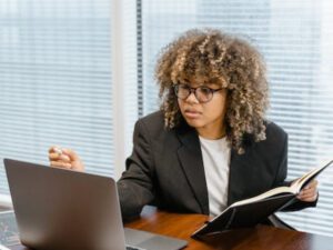 女人一台笔记本电脑和一本书。技能你将学习在学院办公室管理